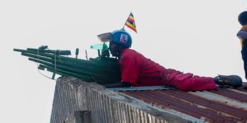 NUP supporter mimicking a military sniper at the roof top during the NUP presidential candidate rally held at Kyegombwa village in Luwero sub county.
