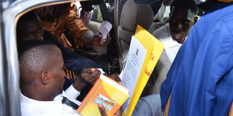 The late councillor-elect Henery Nagwano Kitata struggles to recite the oath of office from inside a vehicle moments before collapsing during the swearing-in ceremony at Nakisunga playground in Mukono District.