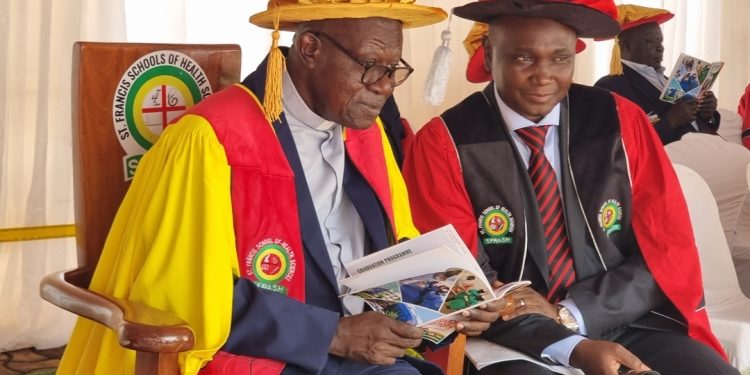 Rev. Fr. Prof. John Chrysotom Maviiri shares a moment with Peter Kiwanuka Bbosa during the 13th graduation ceremony